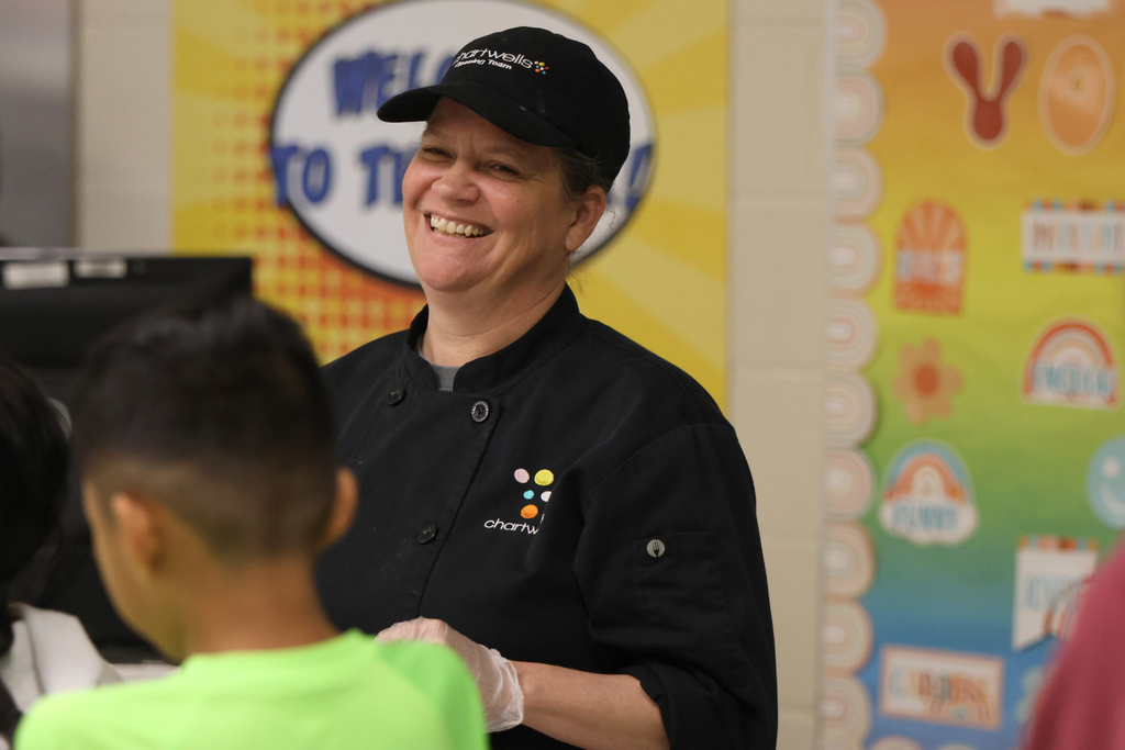 Chartwell employee smiling and serving scholars at a school cafeteria
