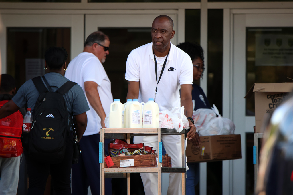 A person pushes a cart filled with half-gallon milk containers. 
