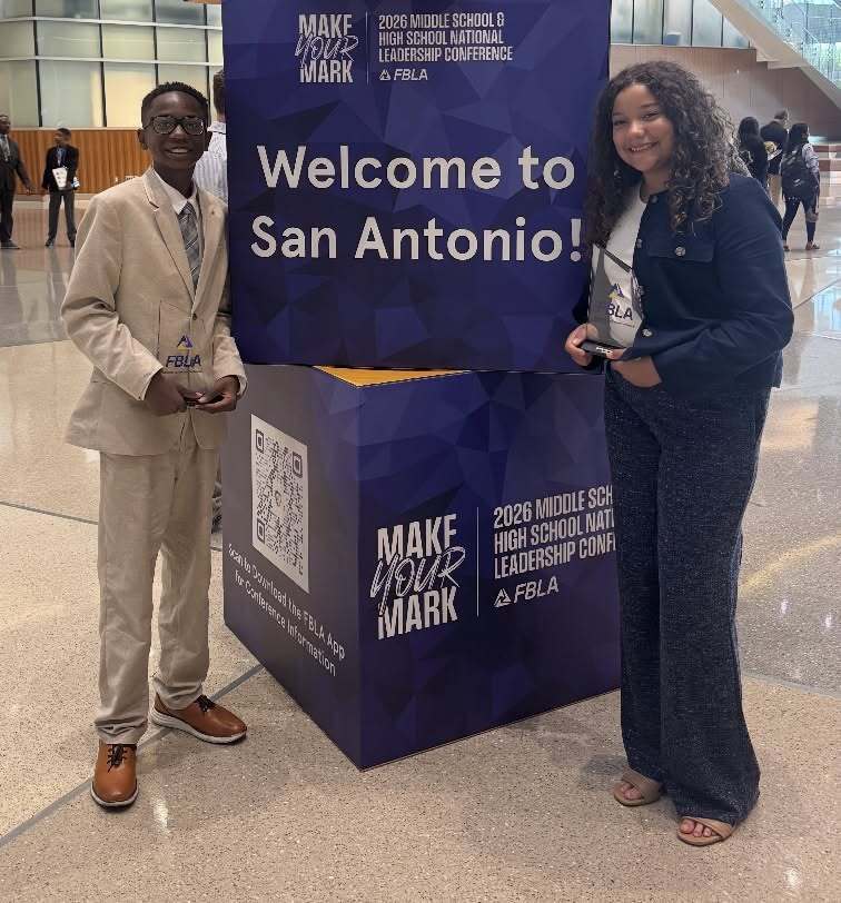 students holding awards next to a "Welcome to San Antonio" sign