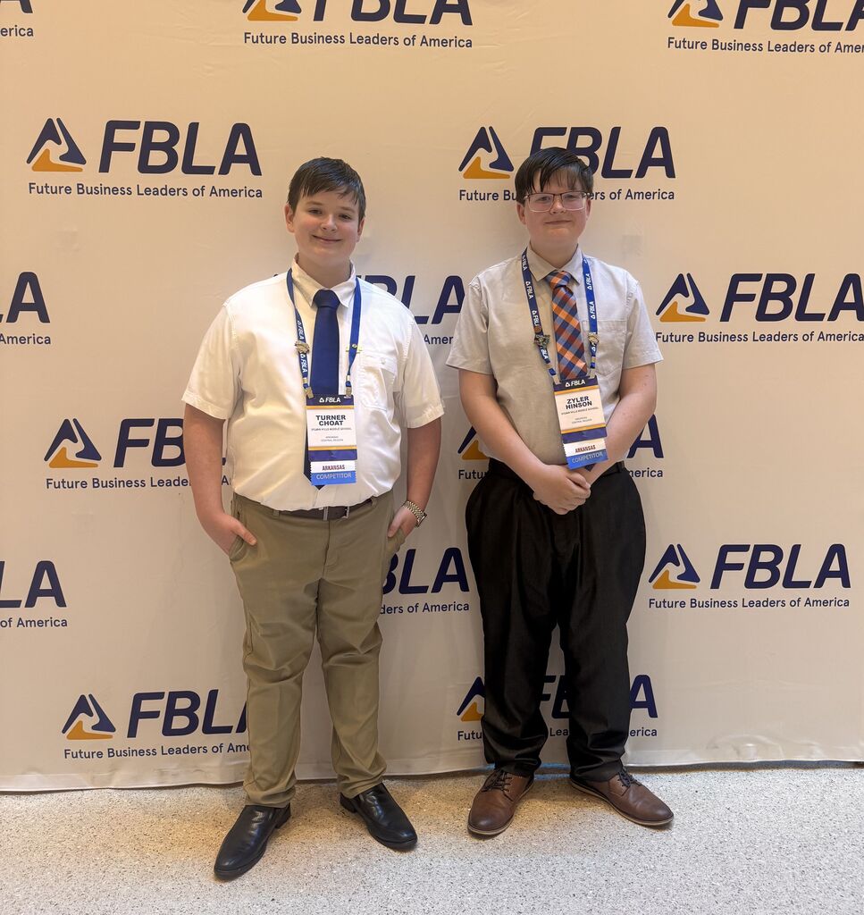 Two students smile in front of an FBLA backdrop
