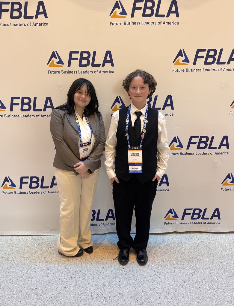 Two students smile in front of an FBLA backdrop