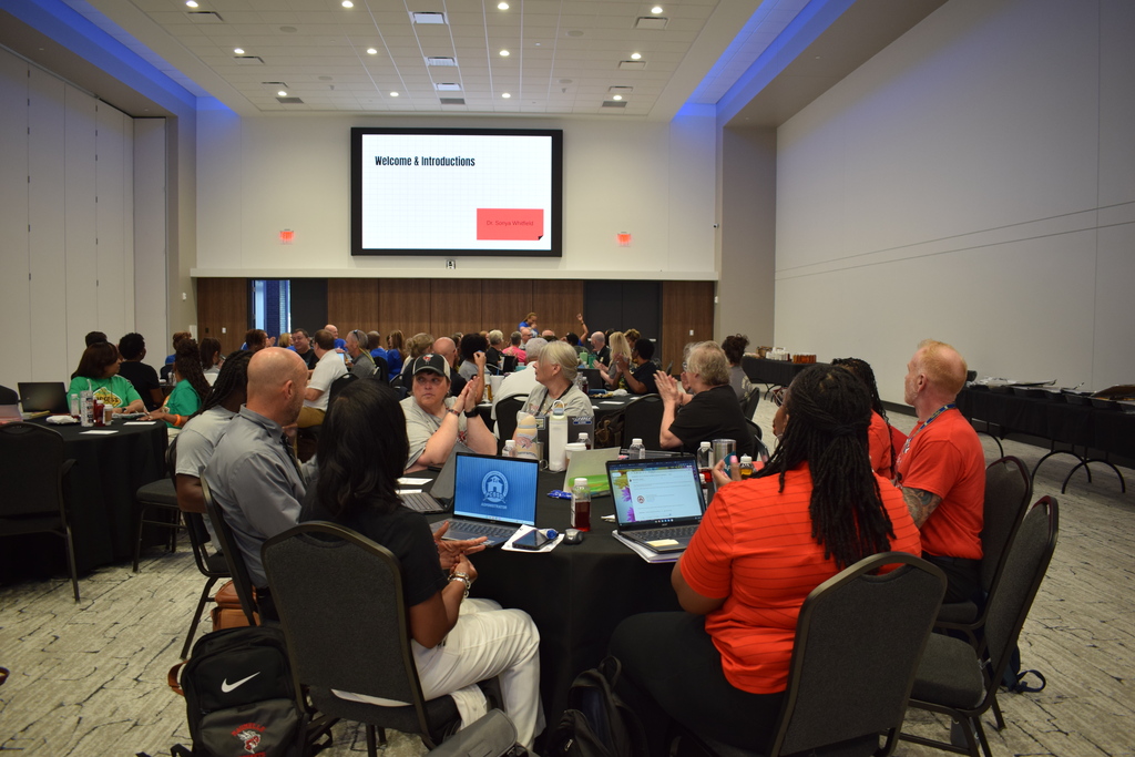 Wide photo of group meeting with people at round tables