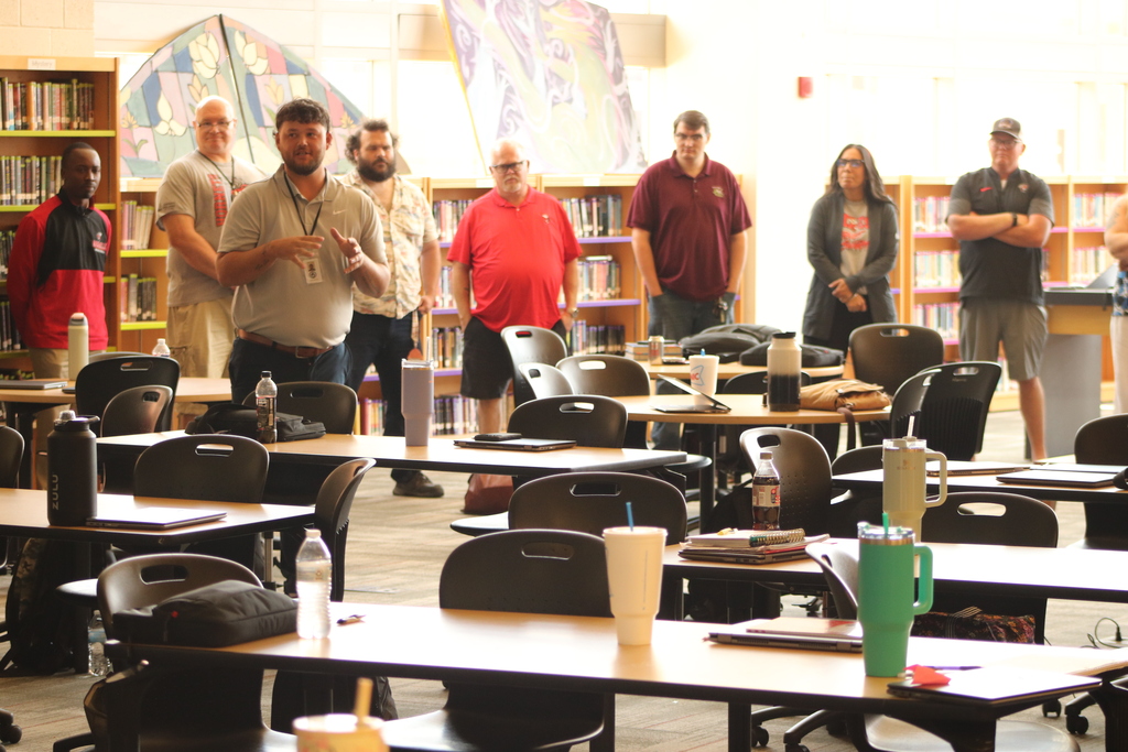 Staff at Maumelle High School stand in a circle during a professional‑development activity, taking turns introducing themselves and sharing something they enjoy.