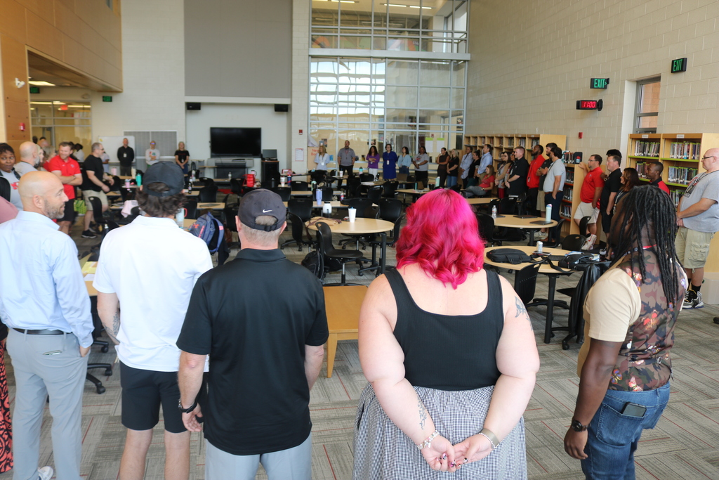 Staff at Maumelle High School stand in a circle during a professional‑development activity, taking turns introducing themselves and sharing something they enjoy.