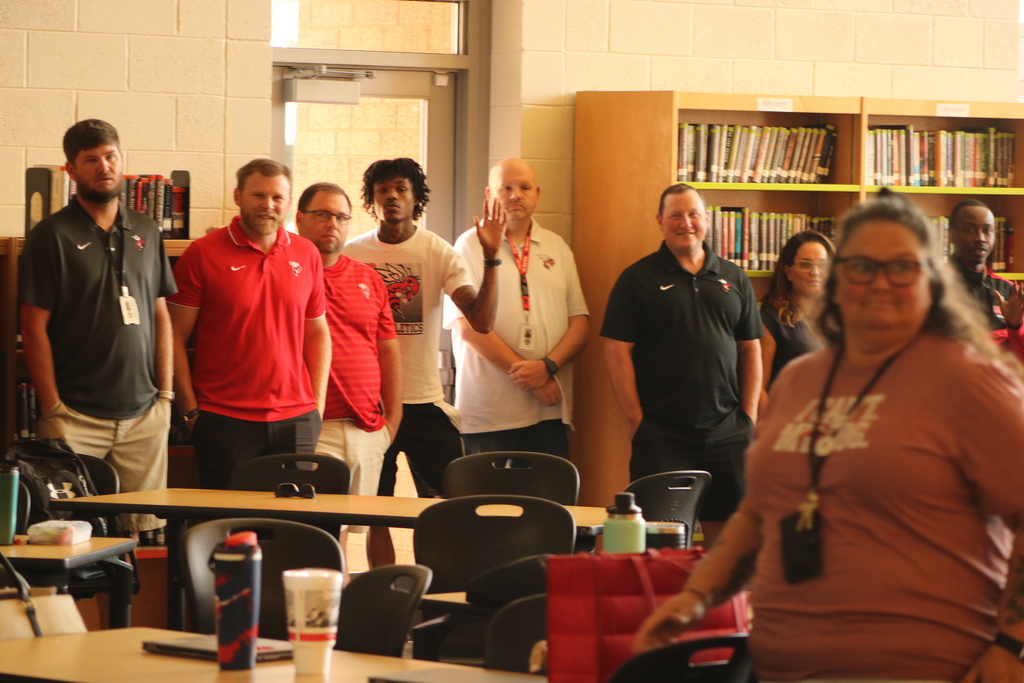 Staff at Maumelle High School stand in a circle during a professional‑development activity, taking turns introducing themselves and sharing something they enjoy.