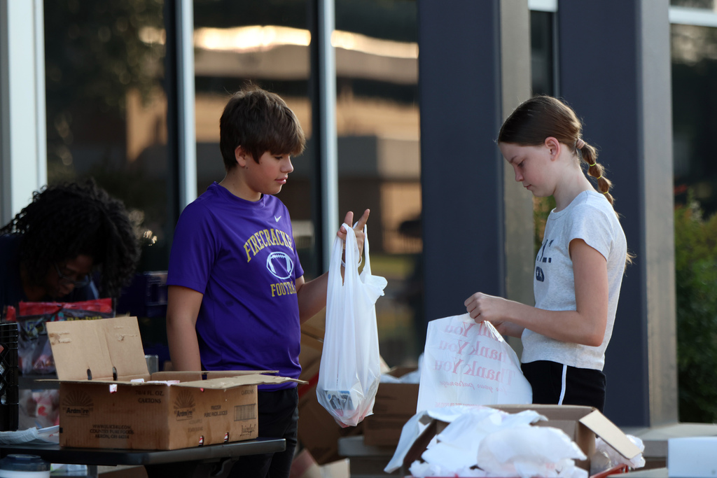 Two students helping bag groceries