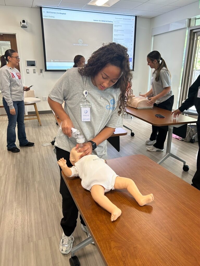 Students in Carti garb giving care to baby doll mannequins