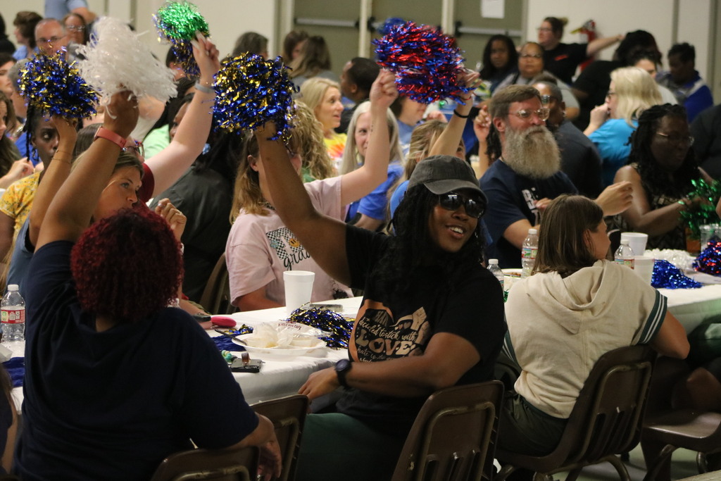 A crowd at a table cheering with pom poms