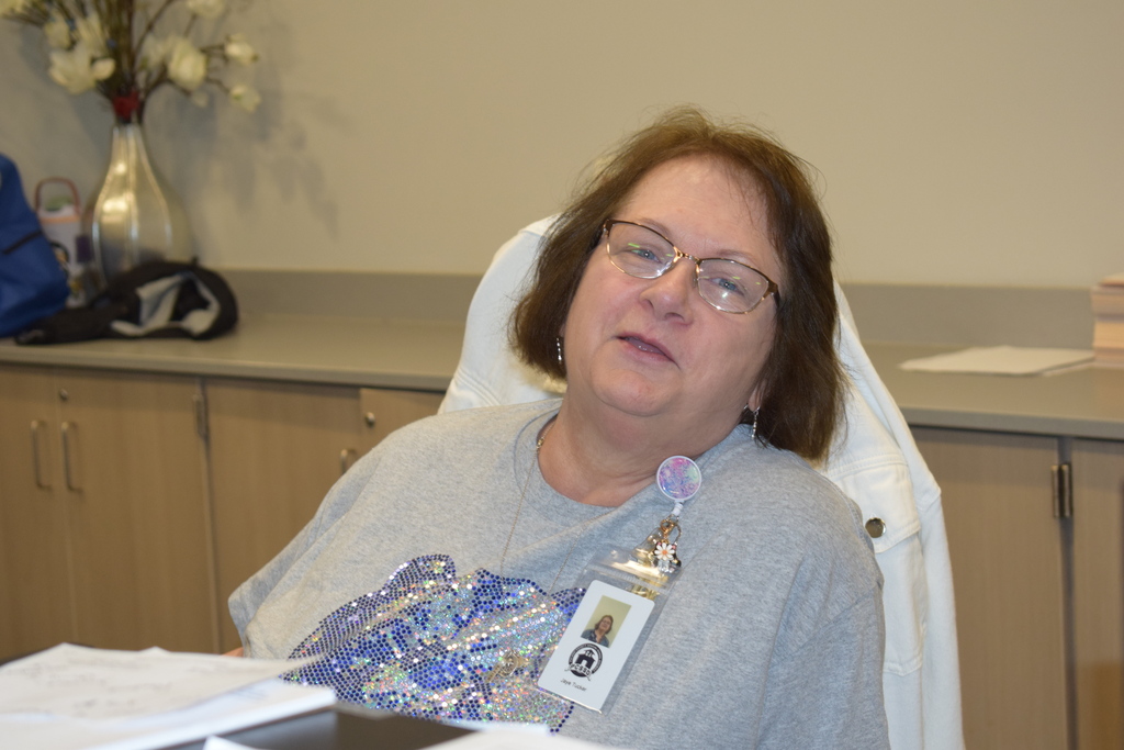 A woman wearing glasses sitting in an office.