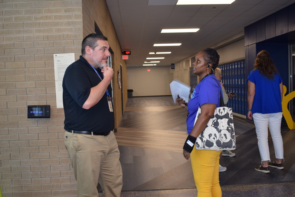 Two people conversing in a school hallway.