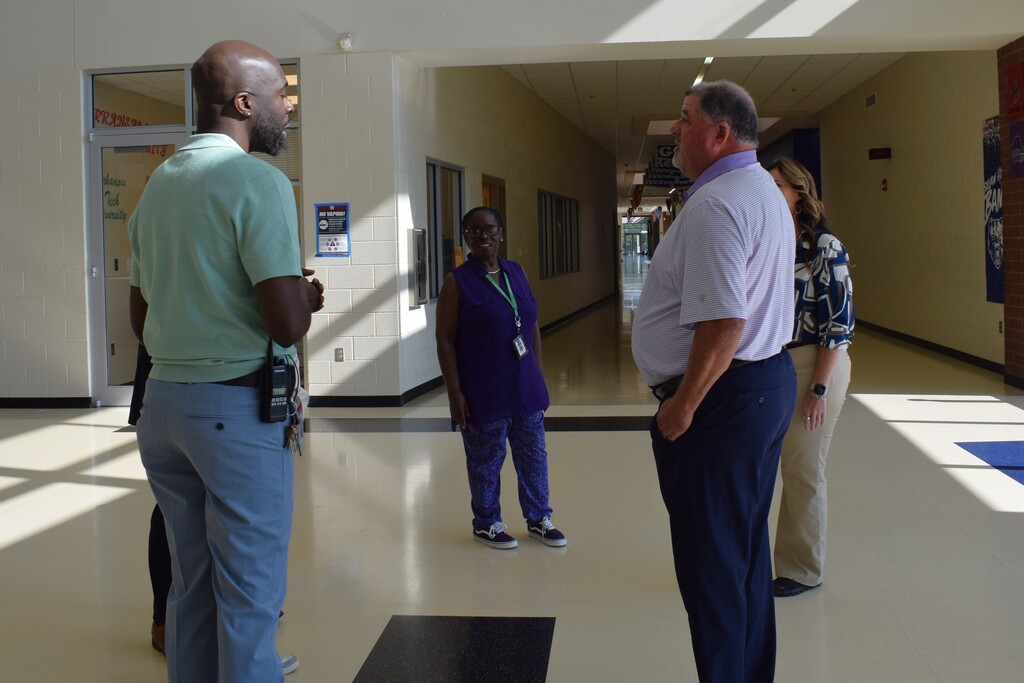 Several people standing and conversing in a hallway.