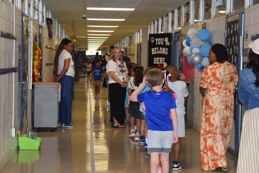 Hallway with students, adults, and a sign reading "You Belong Here".