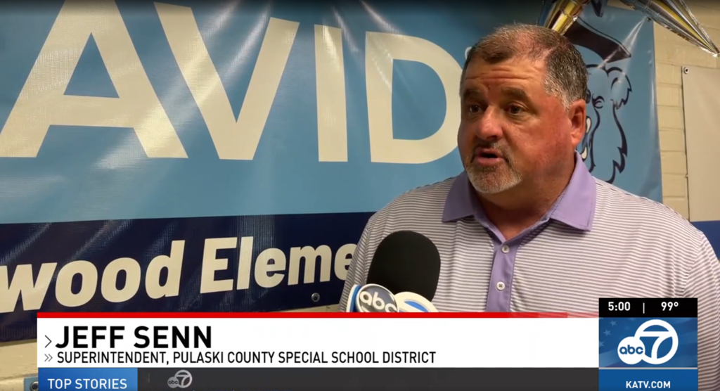 Pulaski County Special School District Superintendent Jeff Senn in collared shirt being interviewed in front of a sign for "AVID Sherwood Elementary"