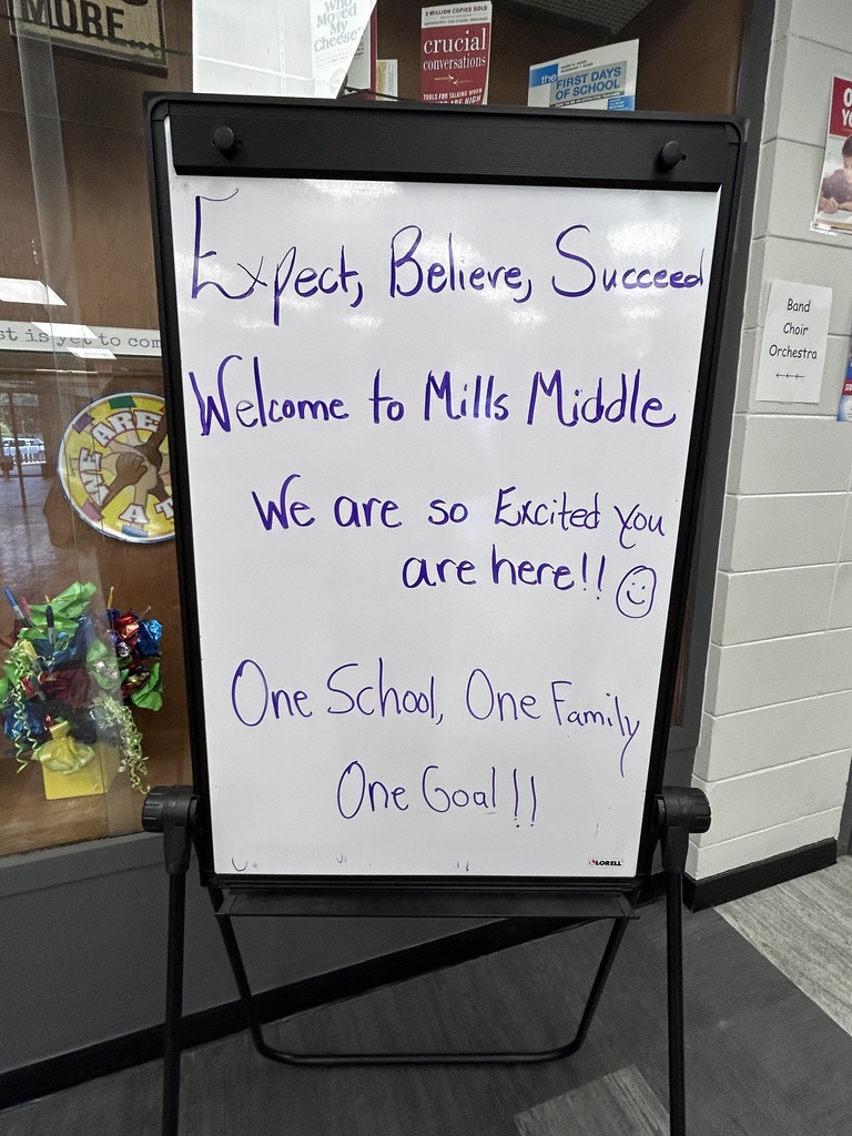 Whiteboard with school welcome message: "Expect, Believe, Succeed. Welcome to Mills Middle. We are so Excited You are here!! One School, One Family, One Goal!"