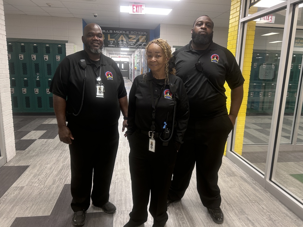 Three security officers in uniform standing together in a hallway.