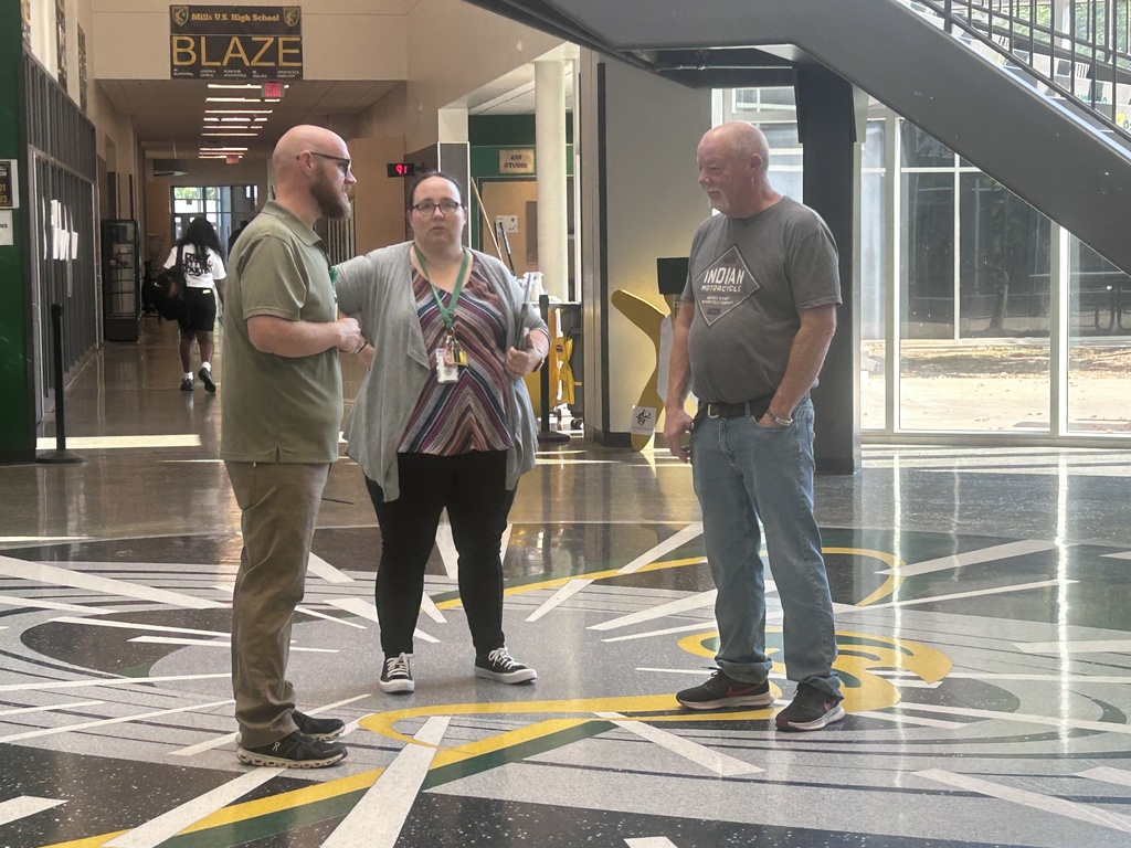 Four adults standing in a lobby with bright flooring and glass walls.