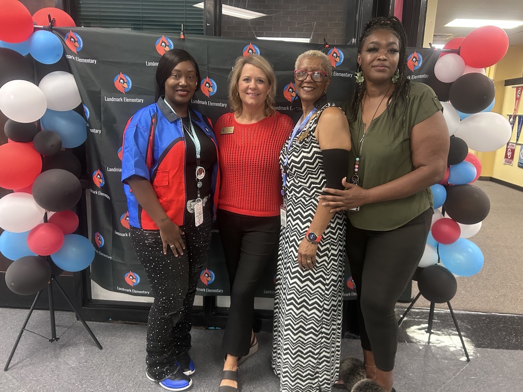 Four women standing in front of balloons in colors of red, white, and blue