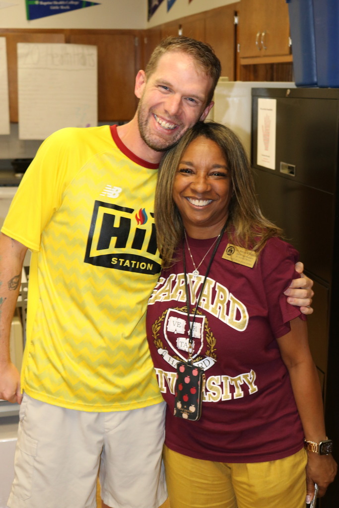 two adults smiling. One is wearing a Harvard shirt.