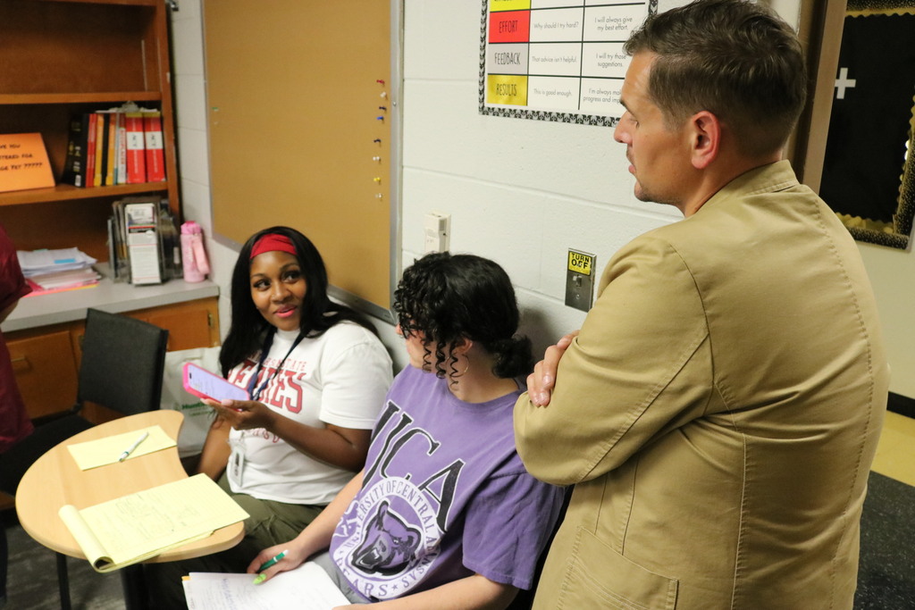 Two people sitting down talking to a person standing up.