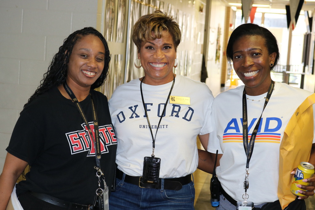 Three women smiling in a hallway in AVID, Oxford & A-State shirts