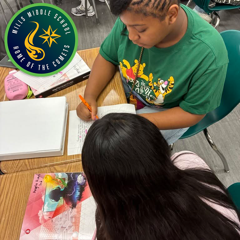 A student writing notes while another looks at her
