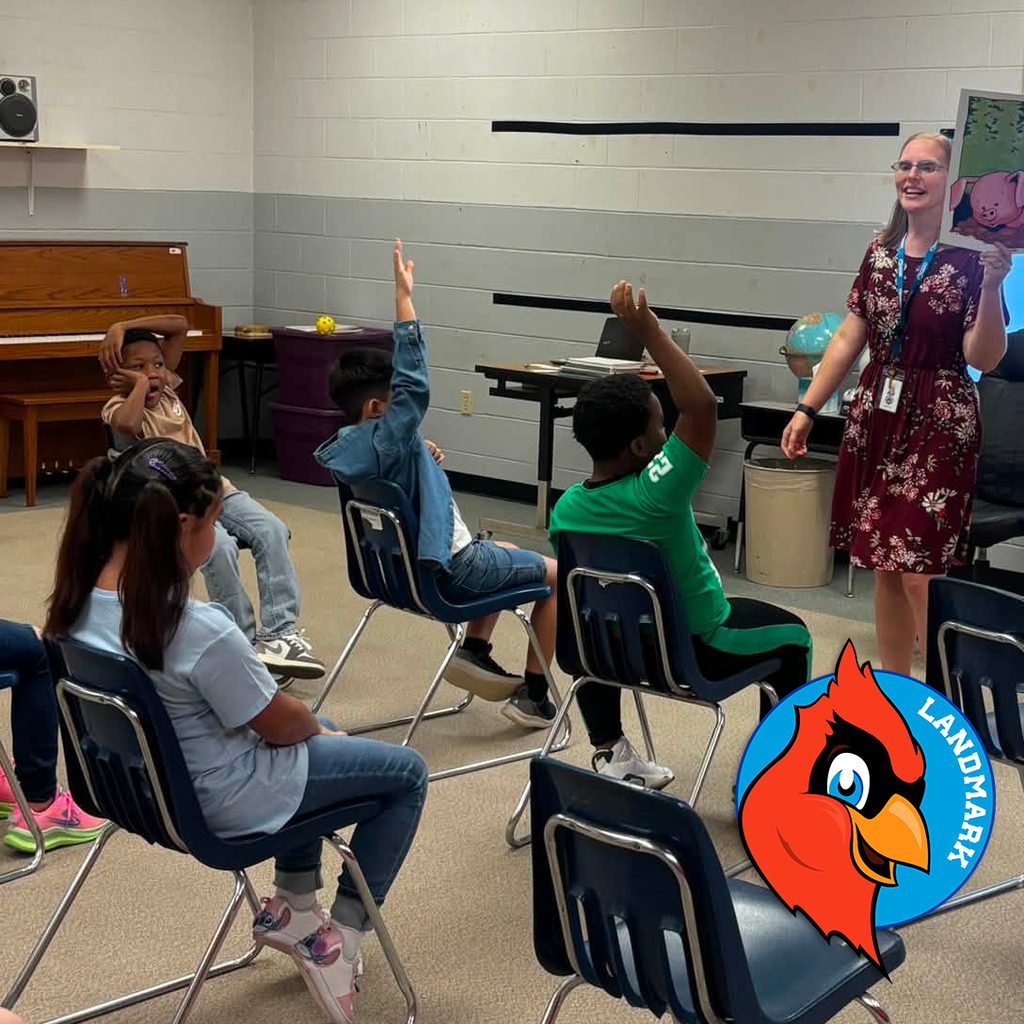 students raising their hand as a teacher raises a book