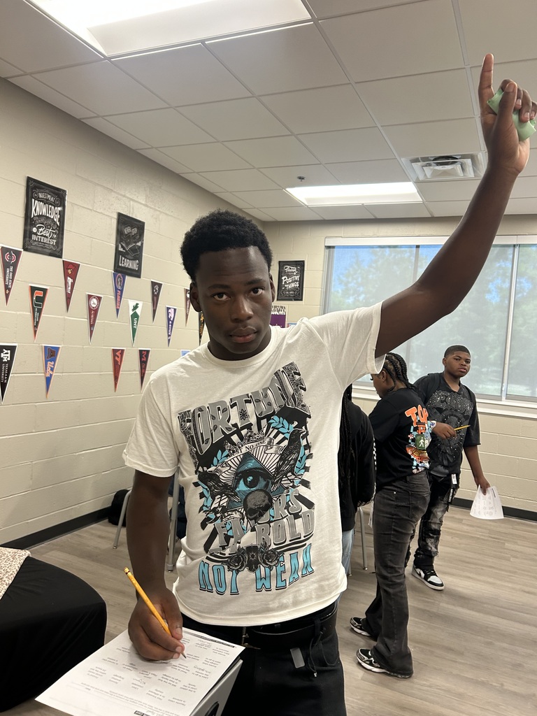 Student writing on paper and raising his hand