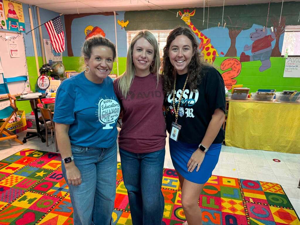 Three people wearing AVID shirts.