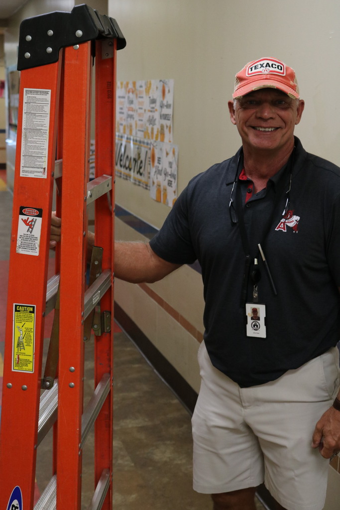 A person wearing an AVID shirt and Texaco hat while holding a ladder.