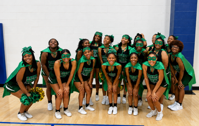 Cheerleaders posting for photo wearing super hero capes and masks