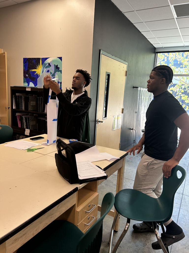 Two students work on their paper sculpture in art class