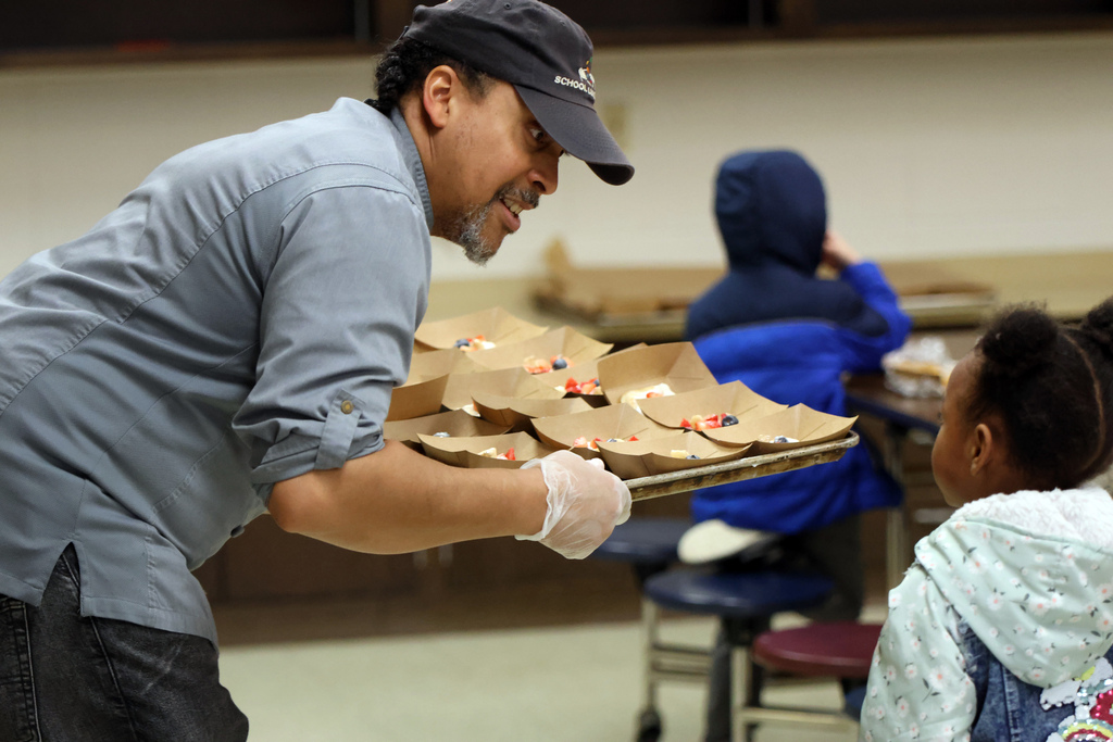 Chef King handing food from a tray to a student