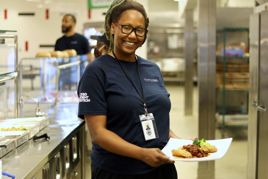 Chef Kiyomi holding a plate of food in a school cafeteria