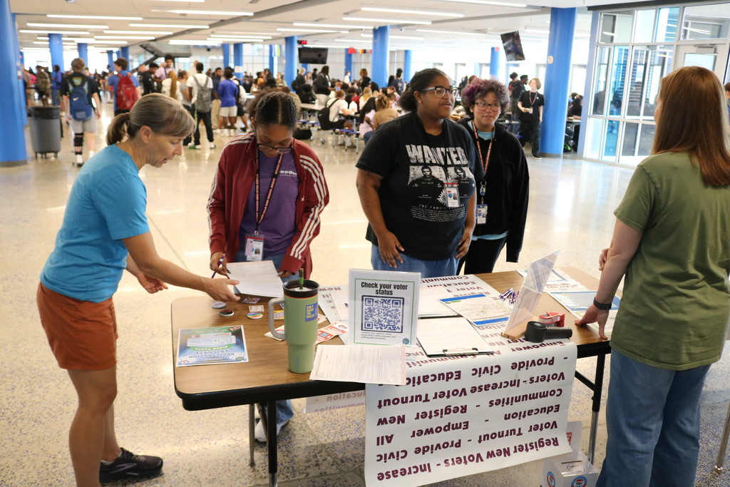 students looking at voter registration papers with adults