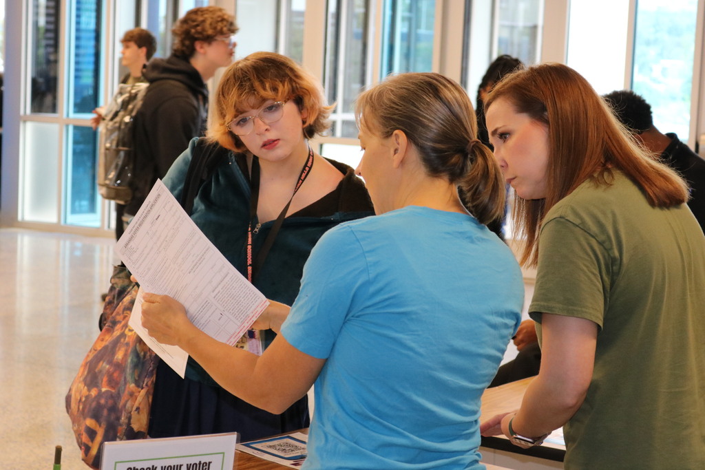 student looking at voter registration papers with adults