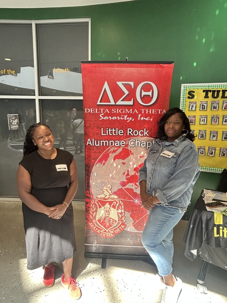 Two women standing beside their delta sigma theta sign