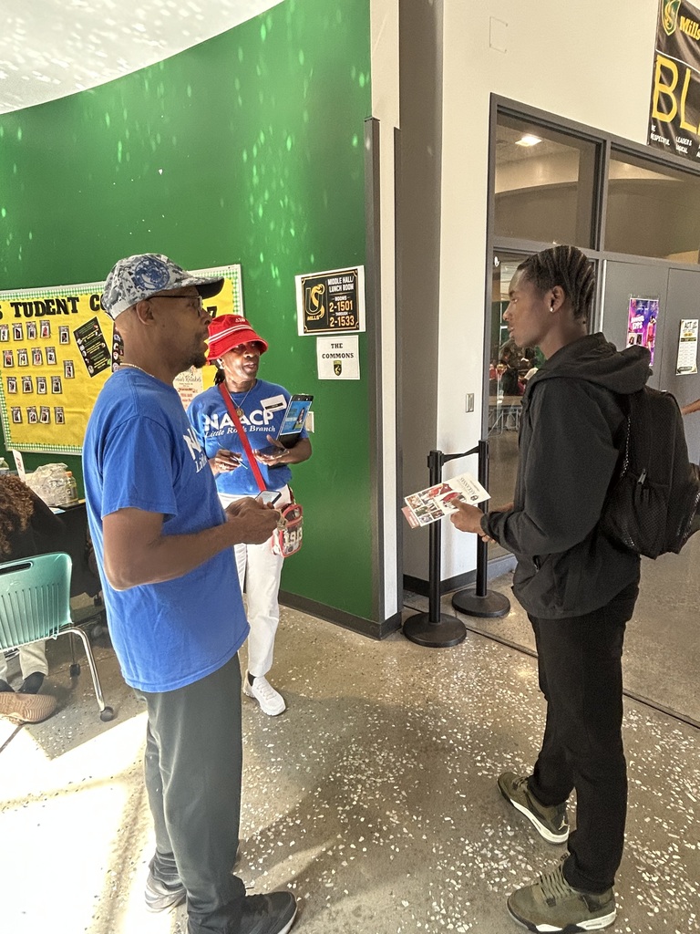 Two volunteers speak to a student in the hallway
