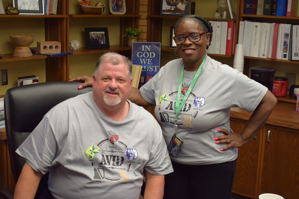 Two PCSSD staff members wearing matching grey AVID t-shirts smile for the camera in an office setting.