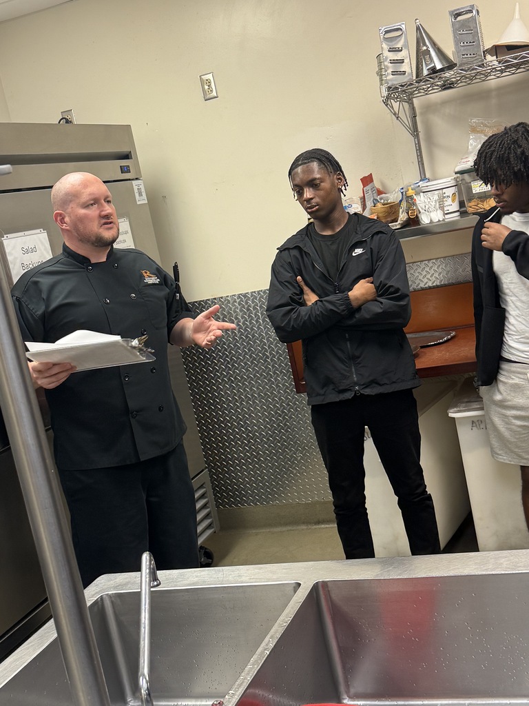 Students in professional kitchen speaking to the chef