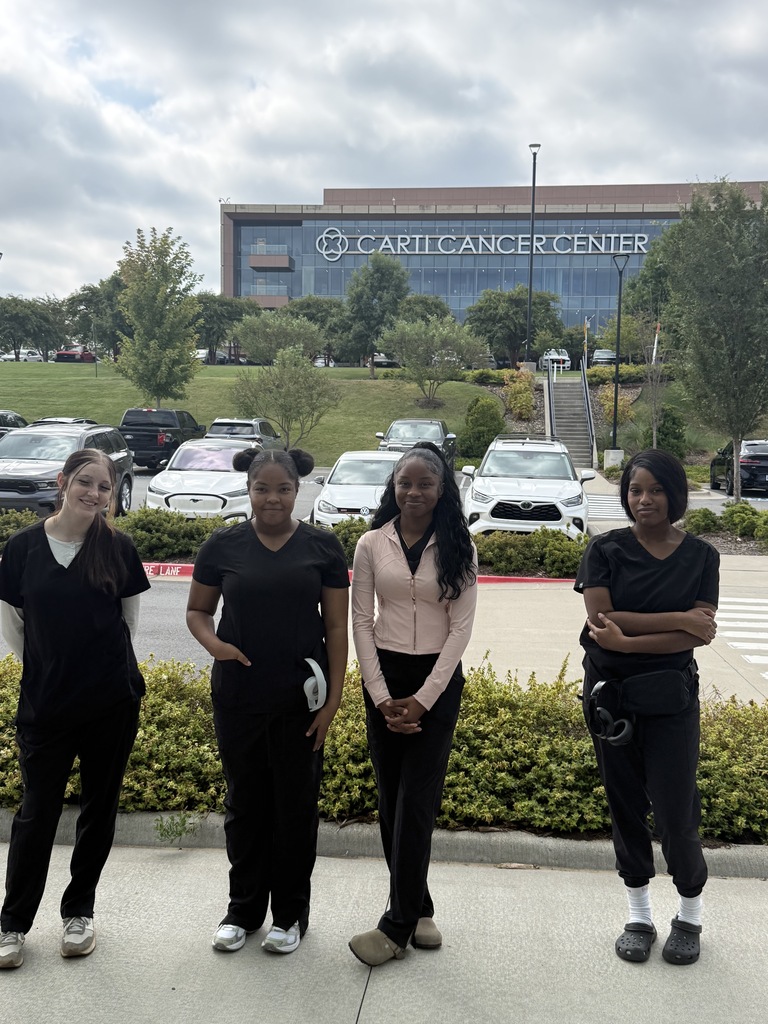 Four students standing in front of the CARTI Cancer Center