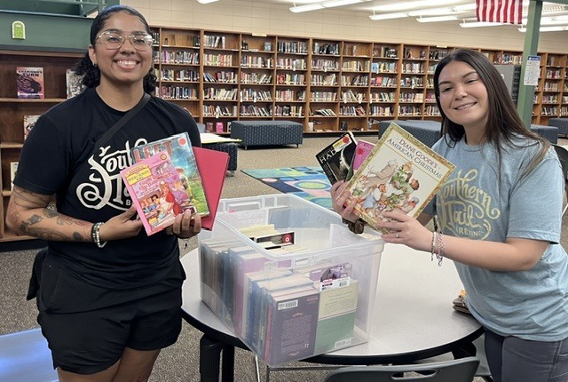 pics of two Southern Tail Brewing employees donating books to MMS for 925 drive
