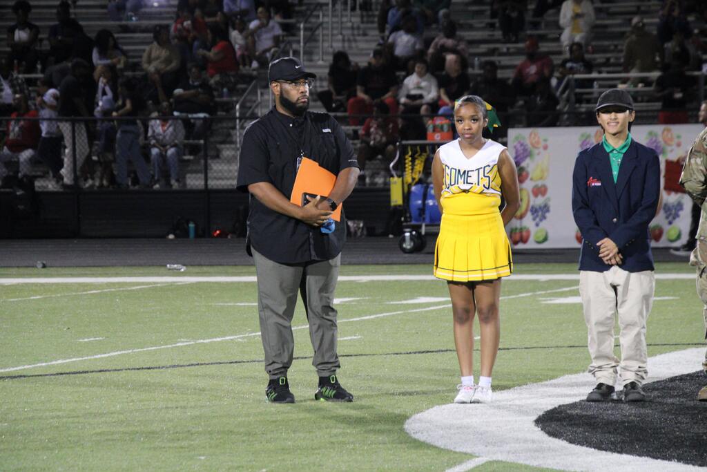 Students, educators, and community partners stand at midfield during Lexicon Academy Night as participants are recognized before the Mills Comets football game.