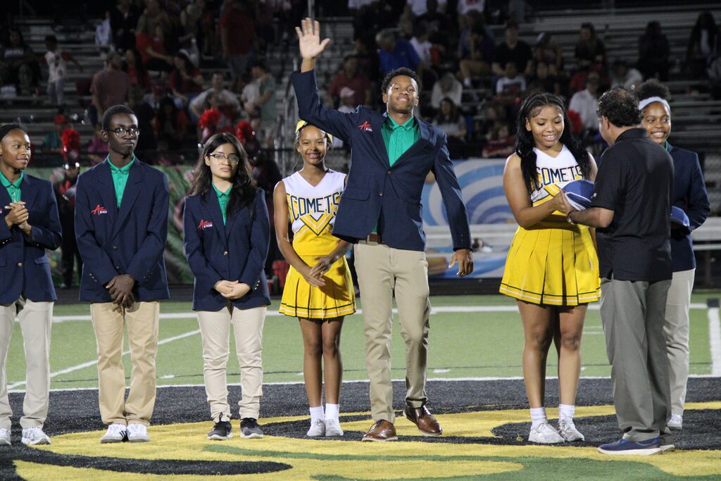 A student waves while being recognized during Lexicon Academy Night as fellow students and community partners stand together at midfield before the football game.