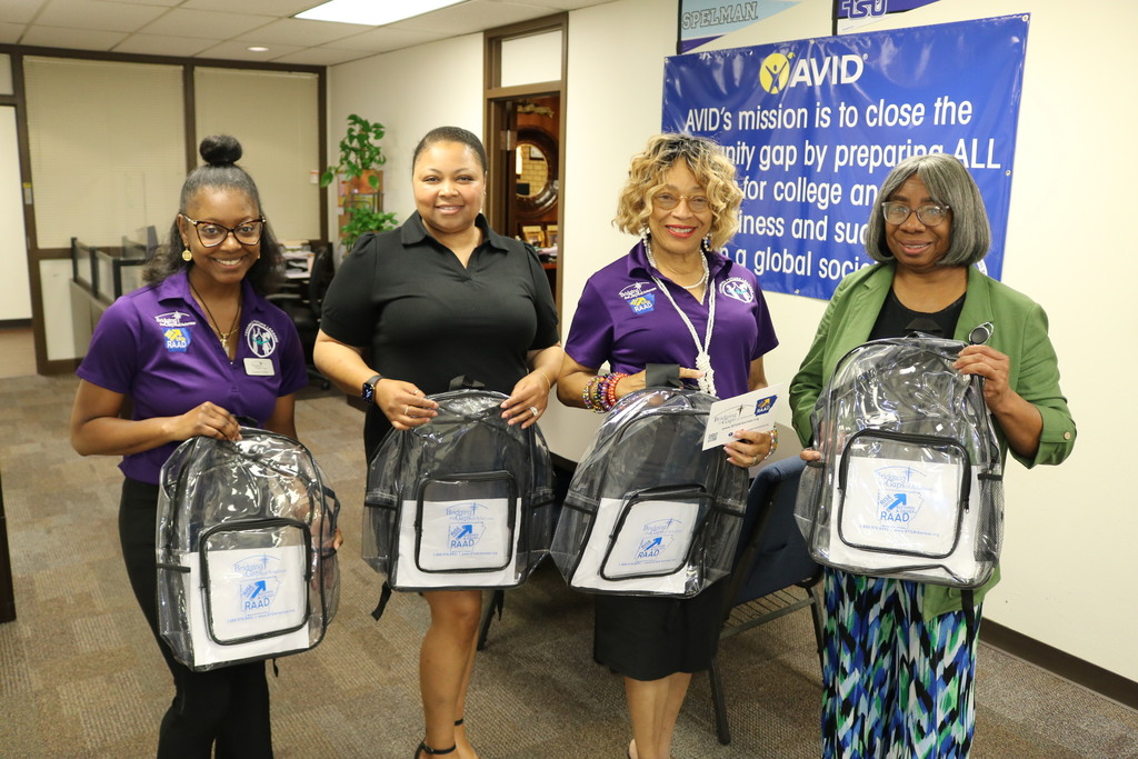 four people hold clear backpacks with Bridging the Gaps of Arkansas branding