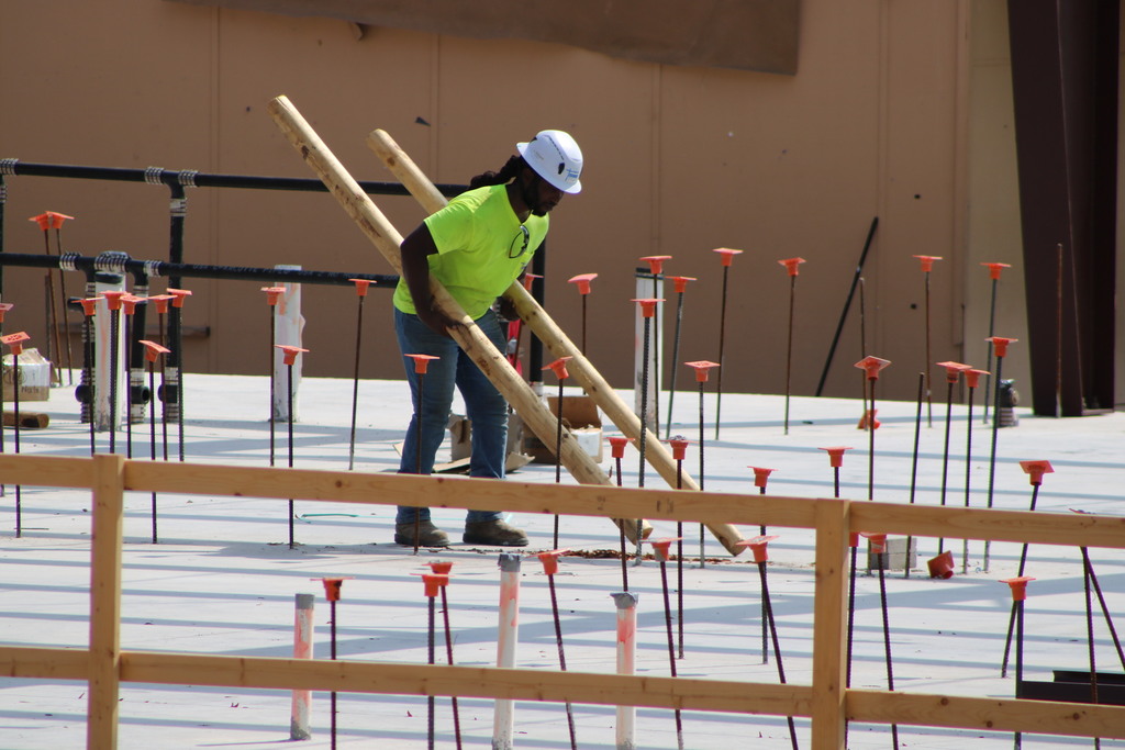 A tight shot of College Station Elementary construction showing a man carrying wood on concrete