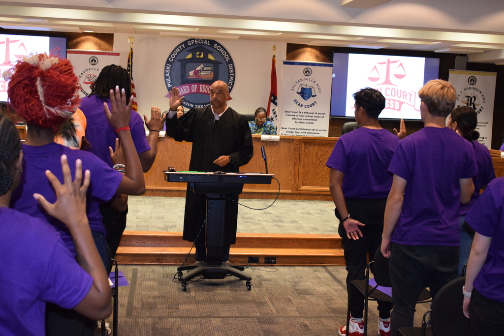 students raising their hands in a pledge