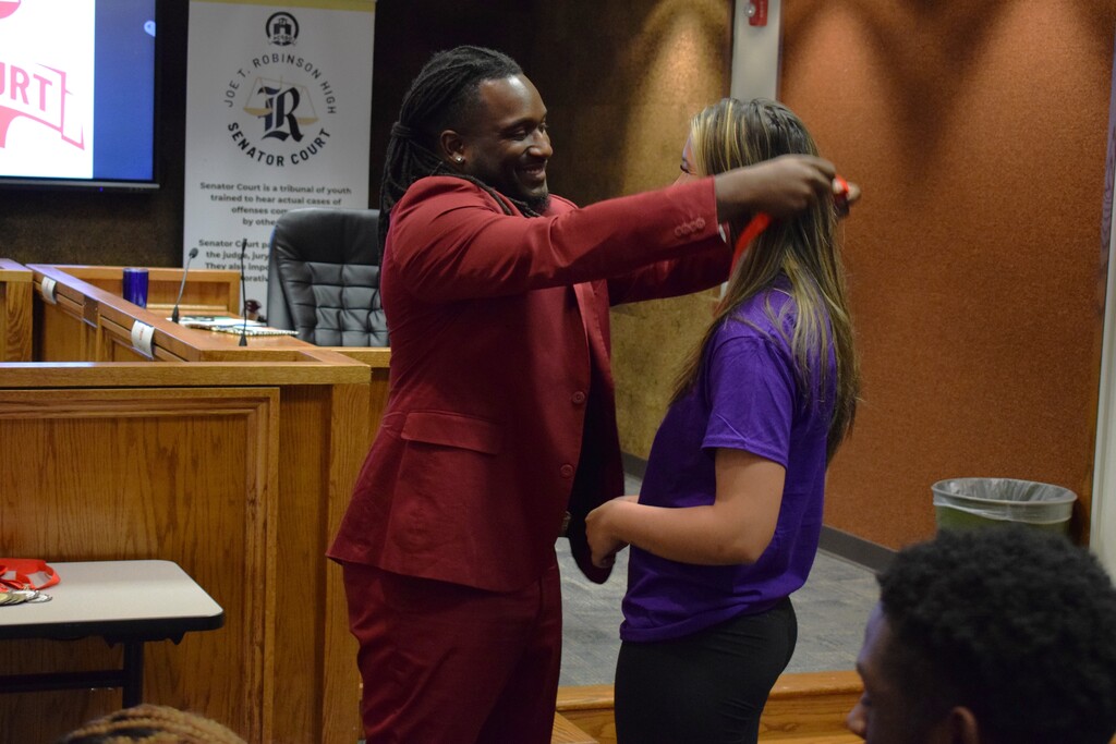 Principal Nick Farr gives a student a teen court medal