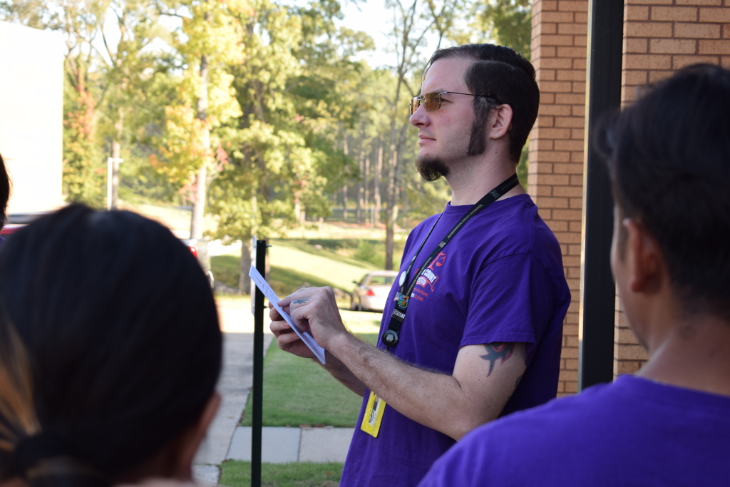 A teacher calls out names from a list her is holding and pointing to.