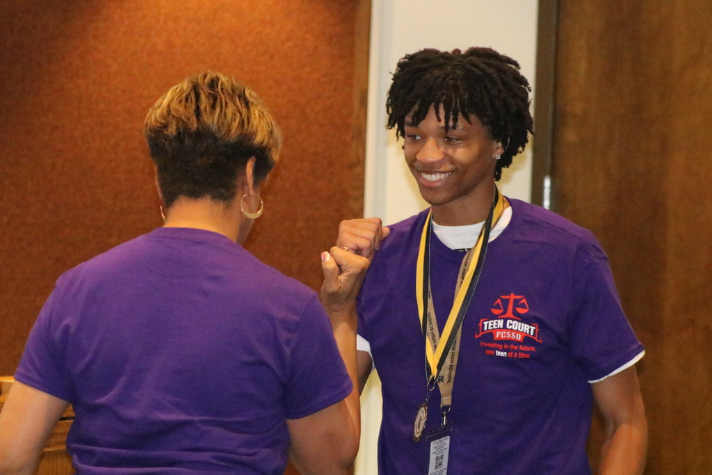 A teen court principal fist bumps a principal after receiving a medal