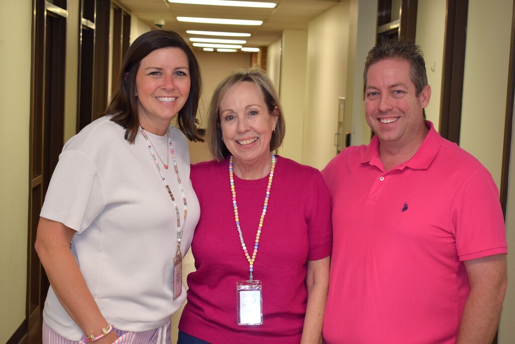 Three Pulaski County Special School District employees pose together in a hallway wearing shades of pink in support of Breast Cancer Awareness Month.